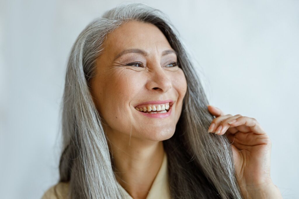 Joyful asian woman with natural grey hair smiles light background 362389 4619 Joyful asian woman with natural grey hair smiles light background 362389 4619