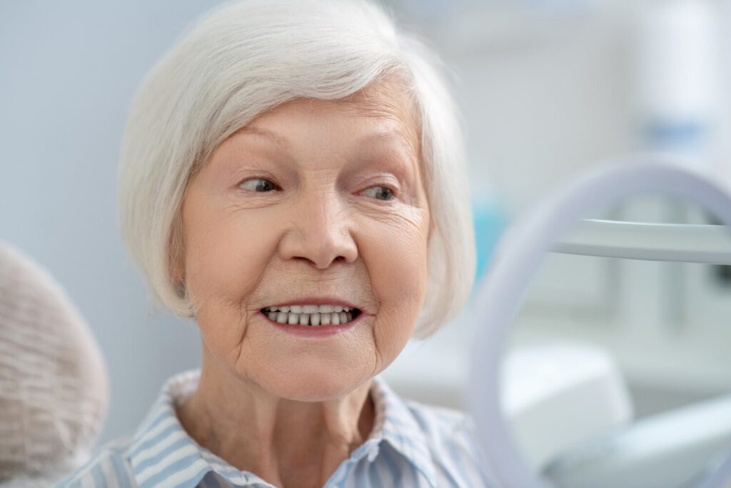 Teeth after restoration senior woman sitting dentists office looking mirror after teeth restoration 465992 724 Teeth after restoration senior woman sitting dentists office looking mirror after teeth restoration 465992 724