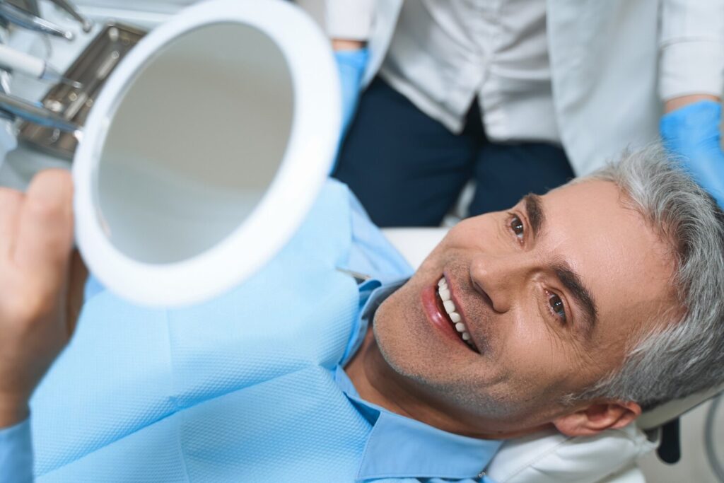 Joyful male is lying chair looking into mirror while being delighted with dentist work 317809 5422 Joyful male is lying chair looking into mirror while being delighted with dentist work 317809 5422