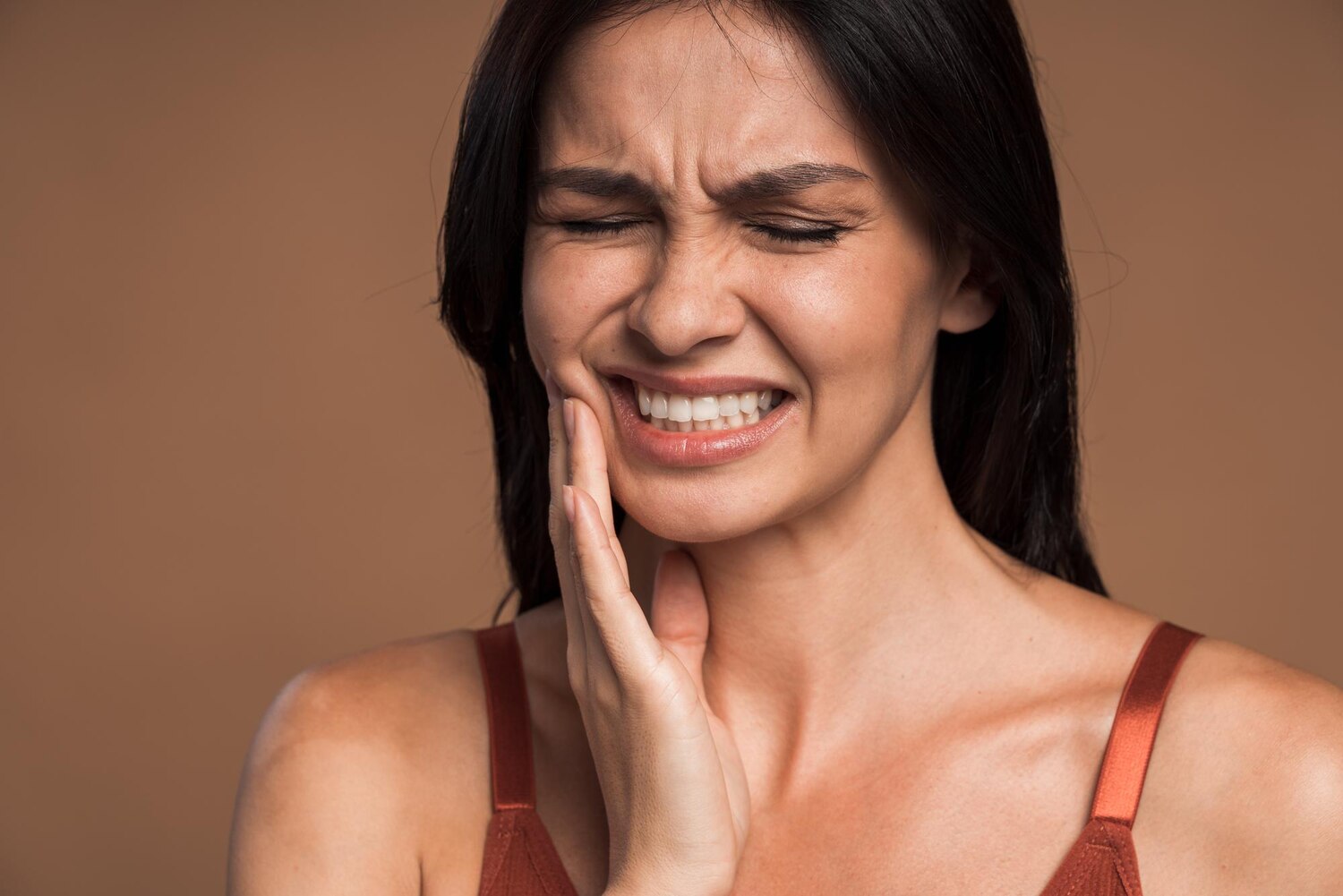 Closeup photo brunette woman pressing her cheek with painful expression because she having terrible tooth ache isolated beige color background 533057 513 Closeup photo brunette woman pressing her cheek with painful expression because she having terrible tooth ache isolated beige color background 533057 513